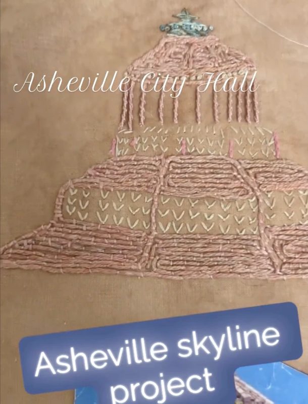 Asheville City Hall hand embroidered in pink and cream stitches on brown cloth