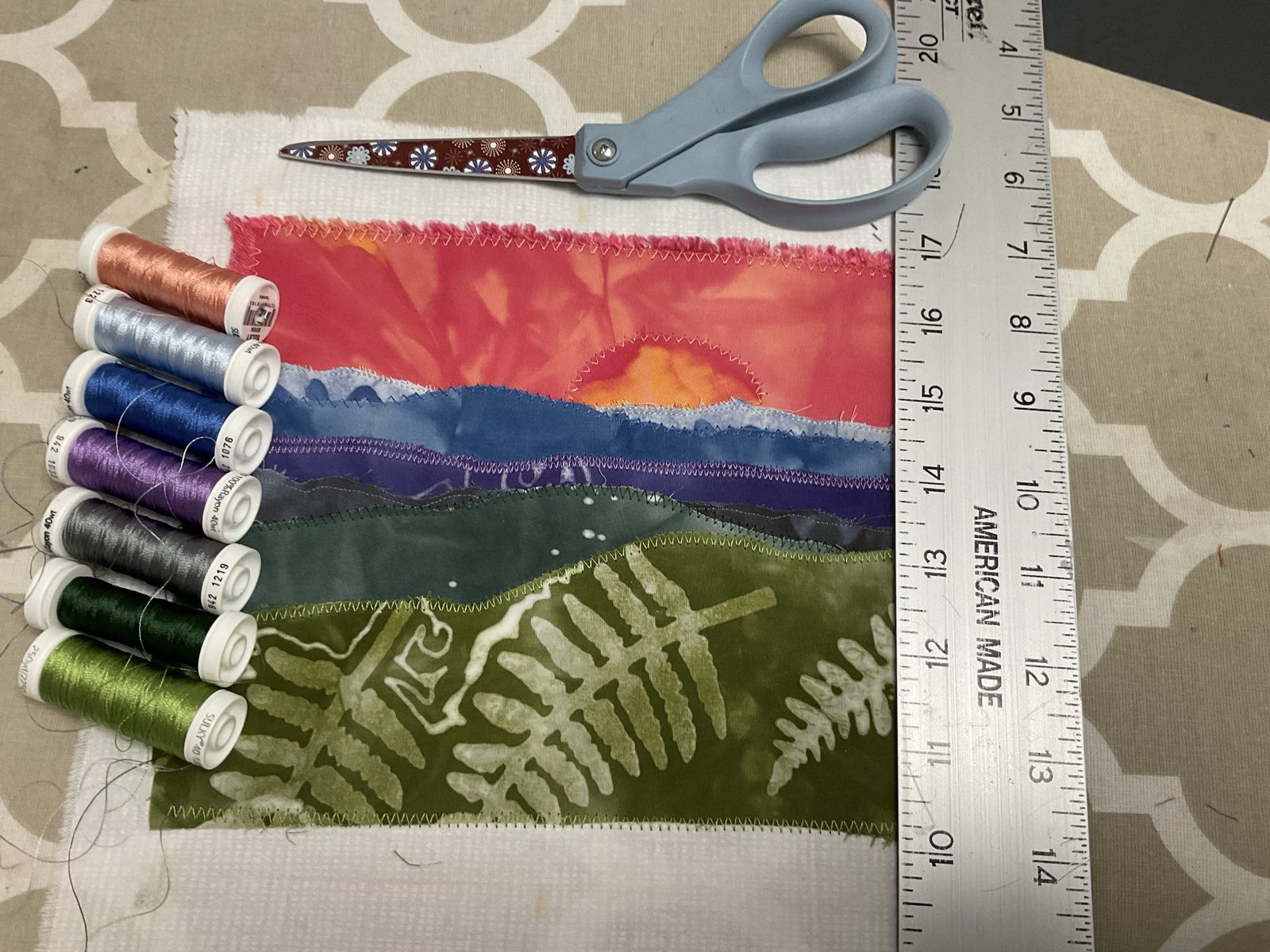 Raw-edge layers of a sunset landscape, each zigzagged down, with the edges left to fray